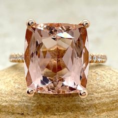 a pink diamond ring sitting on top of a rock