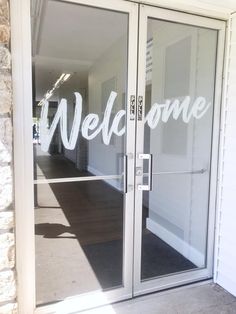 an open glass door with the words welcome on it