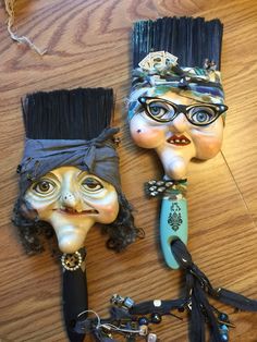 two masks are sitting on top of a wooden table, one is holding a broom