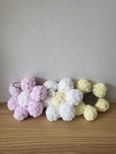 small crocheted flowers sitting on top of a wooden table next to a white wall