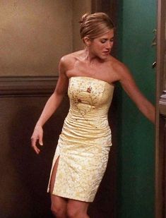 a woman in a gold dress is leaning against a wall and looking at the door