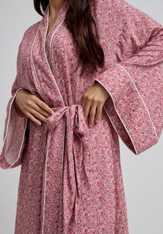 The charming Corina robe is cut from our inimitable cotton and adorned with an interesting pink Ditsy floral print. This oversized kimono-inspired robe boasts fluted sleeves and a detachable belt, creating a flattering silhouette. Contrast piping on the cuff and neck, complete this effortlessly feminine piece.  Cool machine wash only. Wash inside out and with similar colours 100% Cotton Sourced India  Cool machine wash only. Wash inside out and with similar colours Pink Floral Print Kimono For Loungewear, Feminine Floral Print Robe For Loungewear, Pink Spring Kimono For Home, Pink Kimono For Home Use In Spring, Pink Kimono For Home During Spring, Floral Print Long Sleeve Sleep Kimono, Pink Long Sleeve Robe With Floral Print, Pink Floral Print Home Robe, Pink Floral Print Robe For Home