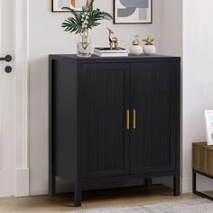 a black cabinet with gold handles in front of a door and pictures on the wall