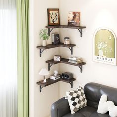 a living room filled with furniture next to a wall mounted shelf above a window covered in green drapes