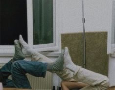 a man laying on the floor in front of a window with his feet propped up