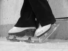 black and white photograph of someone's feet on a skateboard in the snow