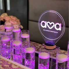 purple lit up glasses and candles on a table with an ad logo in the middle