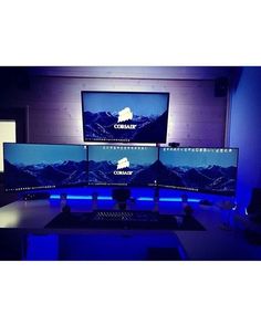 three computer monitors sitting on top of a desk in front of a monitor screen and keyboard