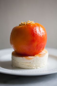 an orange sitting on top of a small piece of food that is on a white plate