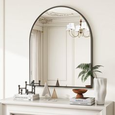 a white fireplace with a mirror on the mantle above it and a potted plant