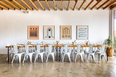 a long table with white chairs is set up in the middle of an empty room