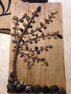 a tree made out of rocks on top of a wooden board with stones around it