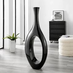 a black vase sitting on top of a hard wood floor next to a white rug