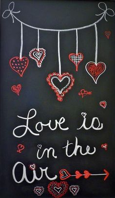 chalk art with hearts hanging from strings and the words love is in the air