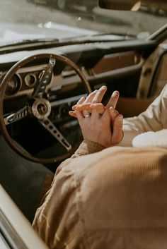 a man sitting in the driver's seat of a car holding his hand up