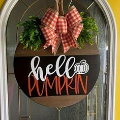 a wooden sign that says hello pumpkin hanging on the front door with a bow around it