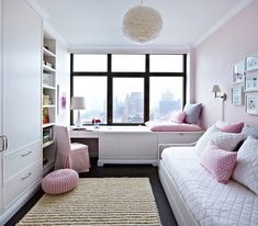 a bedroom with pink and white decor in front of a large window overlooking the city