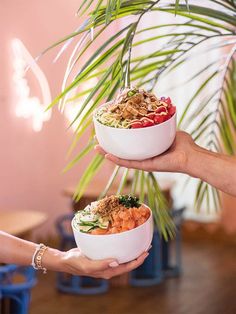 two people holding bowls with food in them