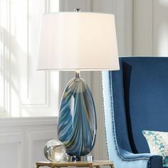 a lamp that is sitting on a table next to a blue chair with a pillow