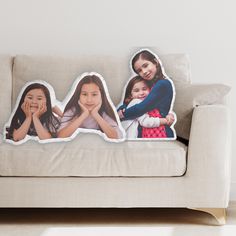 three pillows on the back of a couch with two girls and one is holding their hands together