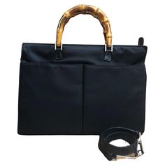 This vintage GUCCI Mini bamboo briefcase handbag is crafted of nylon and smooth calfskin leather in black featuring silver toned hardware and bamboo handles. Top zipper closure opens to a black diamanté jacquard interior featuring a zippered pocket. This Gucci also features two patch pockets at the front and a detachable shoulder strap of the same leather. Made in Italy. Measures approximately 13 x 9.5 x 2 inches Handle drop 4 inches Strap drop 13 inches. Condition - Good vintage condition with minor signs of wear Outside: Some creases on nylon and minor marks on leather. Losing shape Inside: Minimal to no visible signs of wear Smell: No odor Gucci Black Bag With Bamboo Handle, Gucci Black Shoulder Bag With Bamboo Handle, Black Gucci Bag With Bamboo Handle, Formal Black Shoulder Bag With Bamboo Handle, Classic Gucci Bag With Bamboo Handle, Gucci Business Shoulder Bag With Detachable Handle, Gucci Business Bags With Detachable Handle, Gucci Leather Handle Shoulder Bag For Business, Gucci Shoulder Bag With Leather Handles For Business