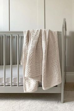 a white crib with a blanket on top of it