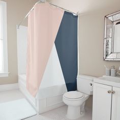 a white toilet sitting next to a bath tub under a bathroom mirror with a pink and blue shower curtain