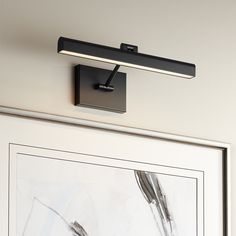 a black light fixture mounted on the side of a wall next to a framed painting