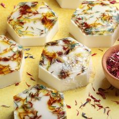 several soaps with flowers on them sitting next to a bowl