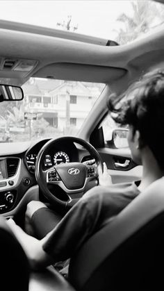 the interior of a car is shown in black and white, with two people sitting at the steering wheel