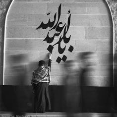 a man standing in front of a wall with graffiti on it's side and writing on the wall