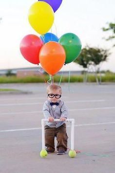 a young boy sitting on top of a chair with balloons attached to it's head