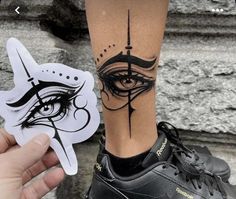 a person with a tattoo on their leg holding up a sticker that has an eye