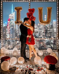 a man and woman are kissing in front of balloons that spell out the word u