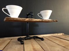 two coffee cups are sitting on top of a wooden tray that is attached to a metal stand