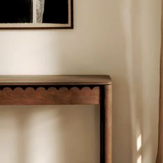 a wooden table sitting next to a window with curtains hanging on the wall behind it