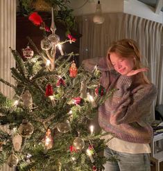 a woman standing next to a christmas tree