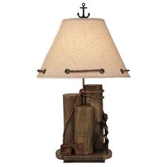 a lamp that is sitting on top of a wooden block with rope and an anchor