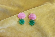 A frosted pink lip shaped stud earring with a dangling green starburst. Each piece has been laser cut from frosted Perspex and is etched with my illustrations. I assemble each piece using sterling silver findings for quality and durability.These earrings are part of my new Strawberry Shortcake collection influenced by the nostalgia and iconography of childhood in the 70's, 80's and 90s. A back to school style collection designed to transport you back to happy memories.>>>>>> Pl Green Star Earrings For Pierced Ears, Lip Earrings, Earrings Acrylic, Lip Shapes, Jewelry Safe, Earrings Pink, Floral Necklace, Jewelry Repair, Pink Earrings