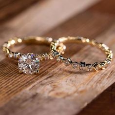 two gold wedding rings with diamond accents on wooden surface, side by side against each other