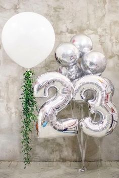 balloons and greenery are displayed in front of the number twenty five balloon bouquets