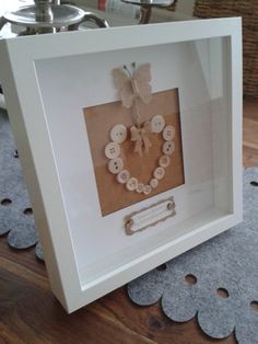 a white frame with buttons in the shape of a heart on top of a wooden floor