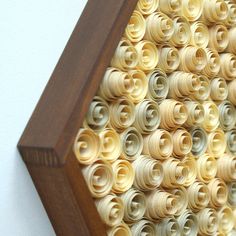 an art piece made out of rolled up paper and wooden frame with holes in the middle