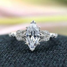 an engagement ring with a pear shaped cut diamond in the center, on top of a black cloth