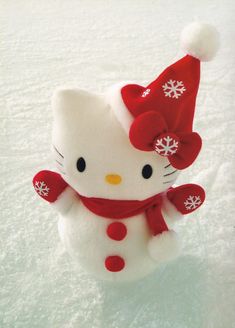 a hello kitty stuffed animal wearing a red hat and scarf with snowflakes on it