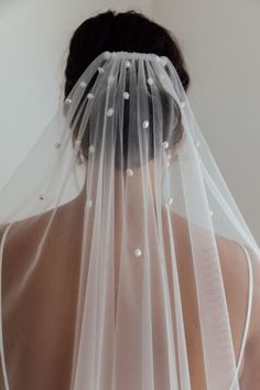 the back of a woman wearing a wedding veil with pearls on it's head