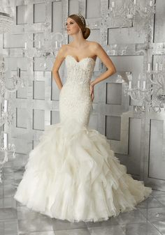 a woman in a white wedding dress standing next to a wall with crystal chandeliers