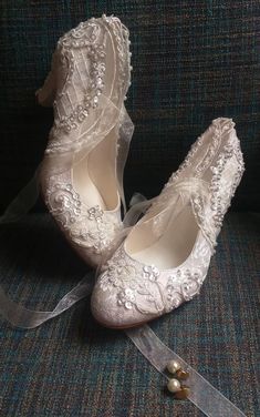 two pairs of white wedding shoes sitting on top of a couch