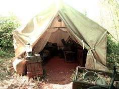 a tent in the woods with lots of furniture inside