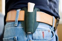 a close up of a person wearing jeans and holding a knife in their back pocket